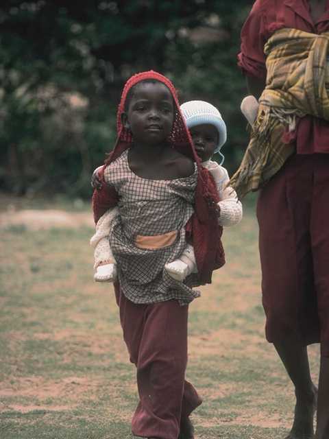 Niño africano con bebé en la espalda